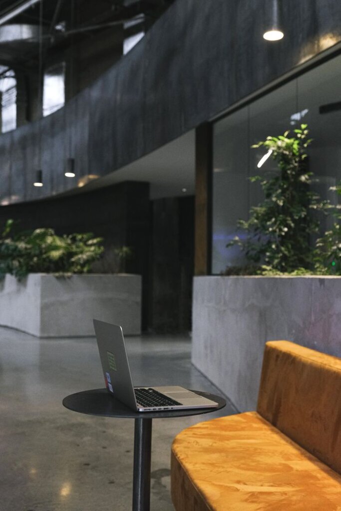 Sleek modern office space with a laptop on a round table beside a comfortable sofa.