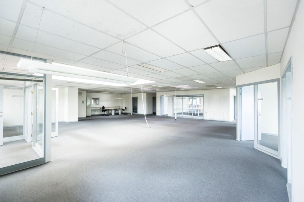 Bright empty office space featuring minimalist design and glass partitions.