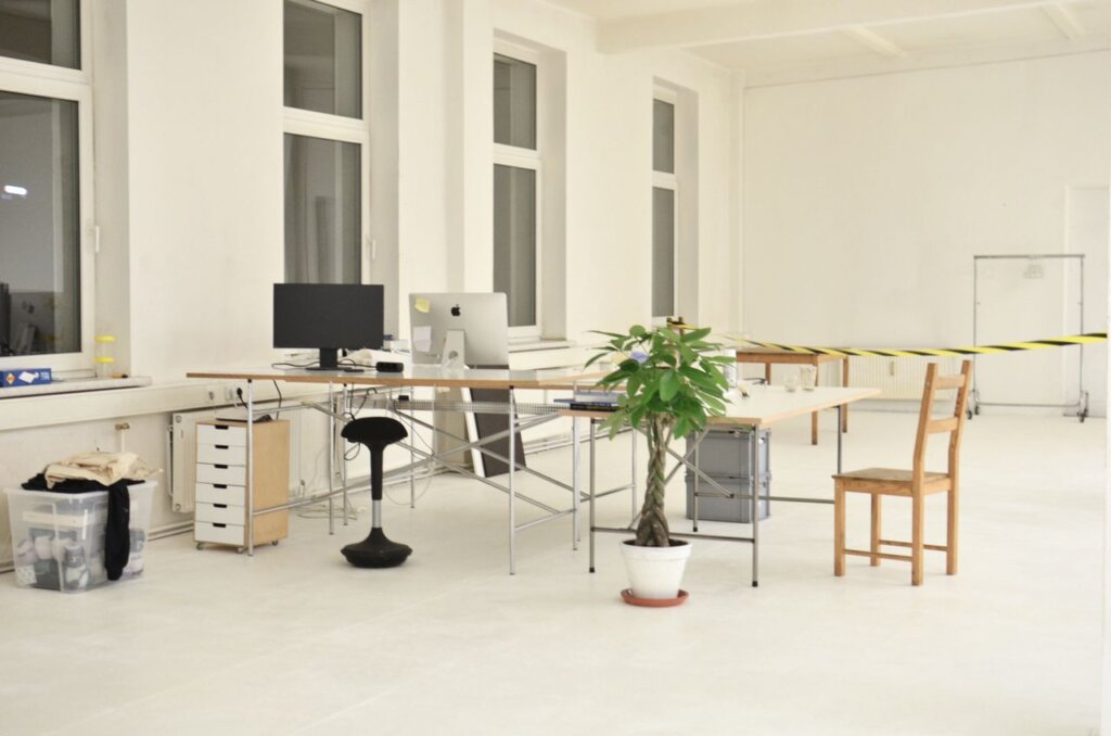 Modern workplace interior with computer monitors and potted plants in open space office building with striped tape at closed area